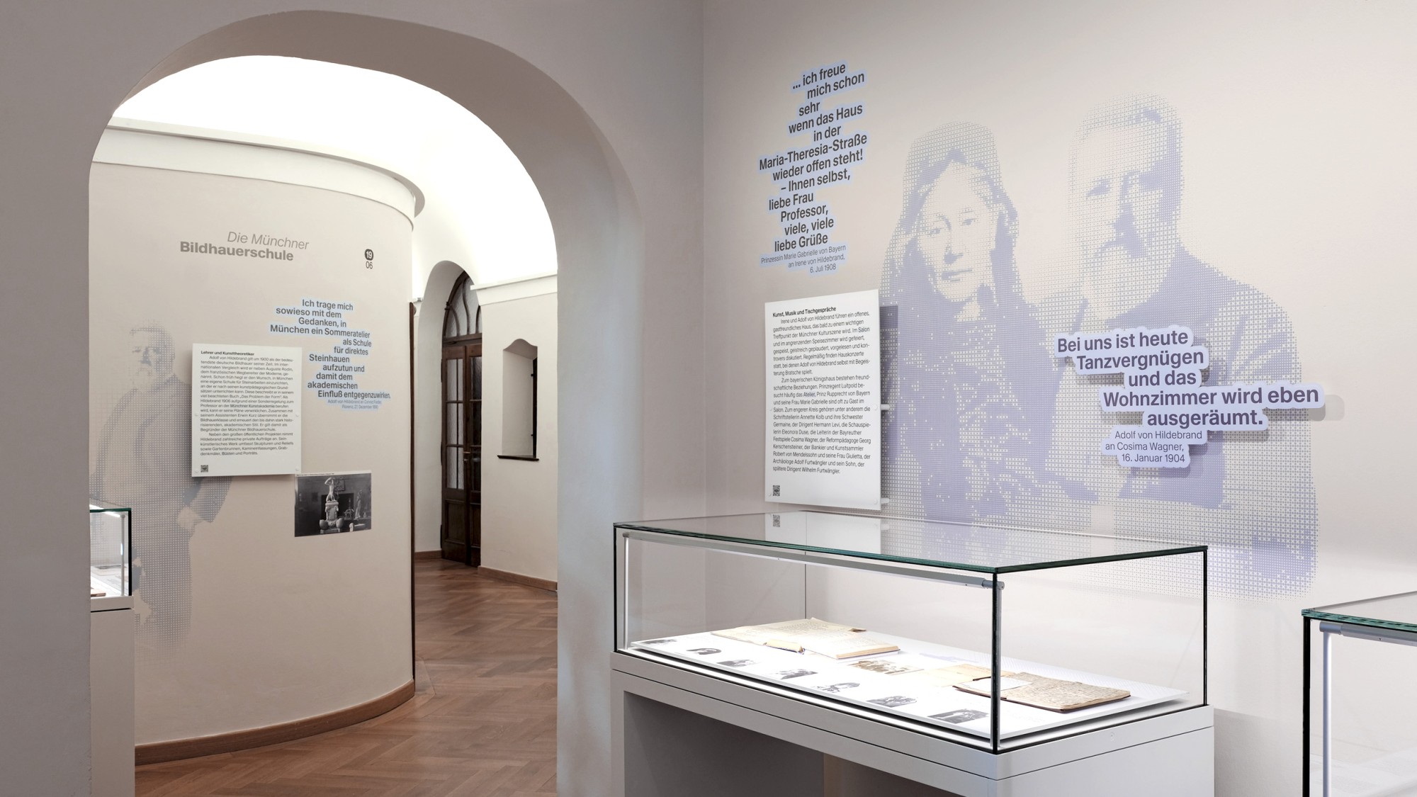 Einblick aus dem inneren der Ausstellung mit Porträts wichtiger Persönlichkeiten an den Wänden und seltene Fundstücke in Vitrinen.