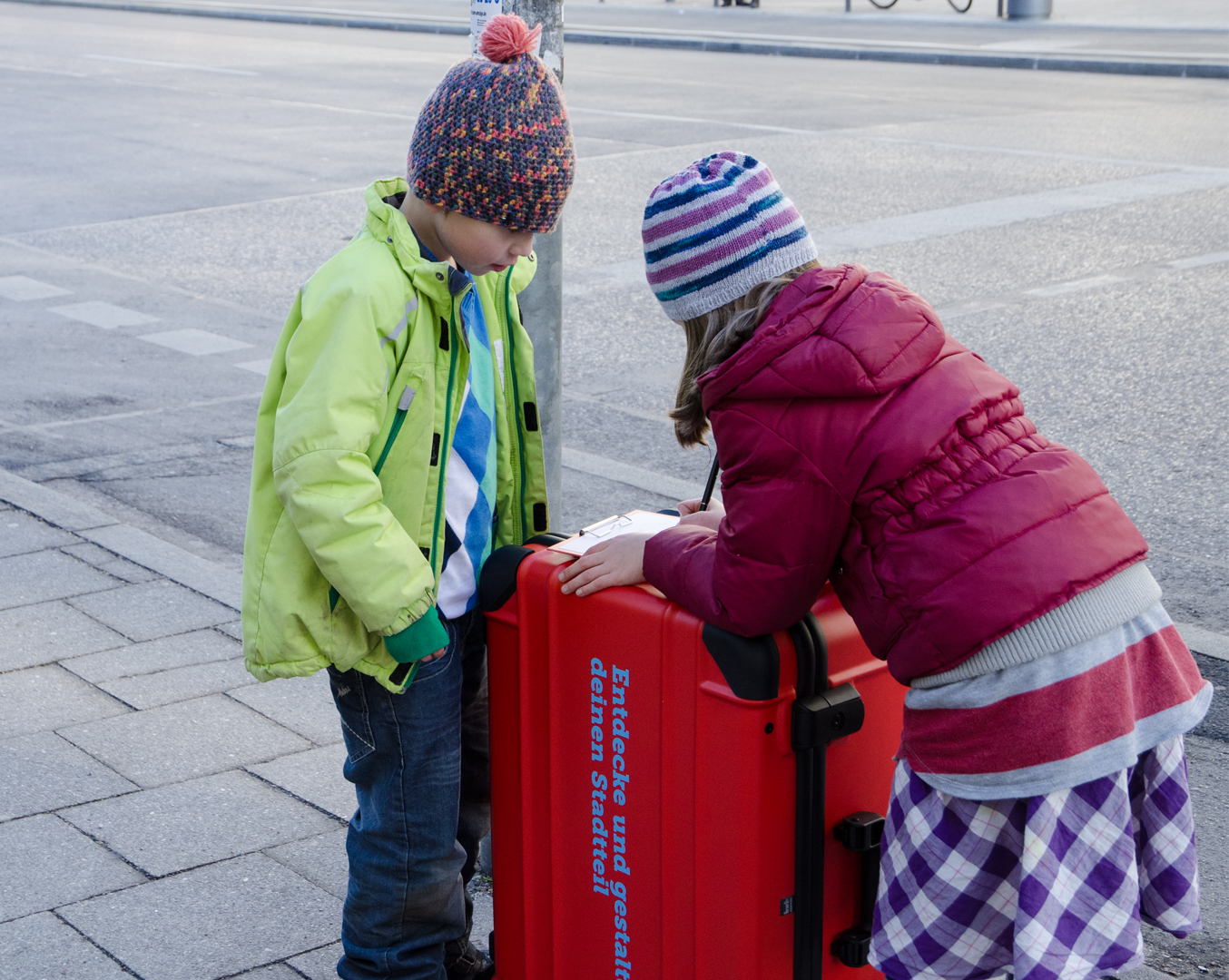 Fotografie von 2 Kindern und einem großen roten Koffer.