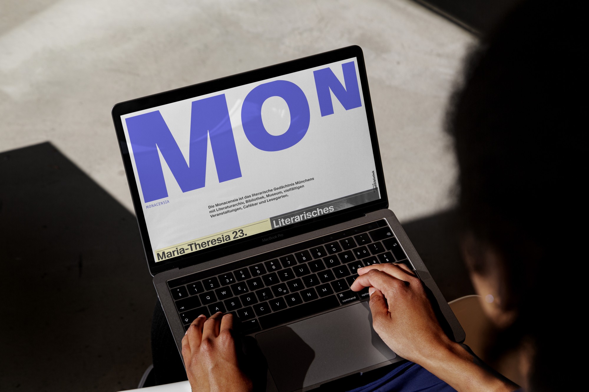 Laptop mit einem Ausschnitt aus der Website der Monacensia. Prägnant im Vordergrund ist dabei das große Logo MON in violetter Farbe. Branding Agentur München – Markenentwicklung und Corporate Design für den Internetauftritt