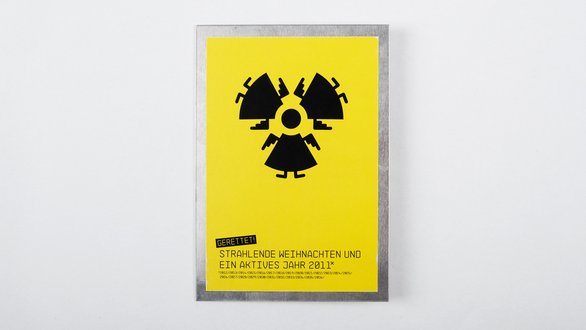 Mittig bilden Engel Symbole ein Atomkraftwerk Zeichen. Unten steht der Schriftzug: „Strahlende Weihnachten und ein aktives Jahr 2011“.