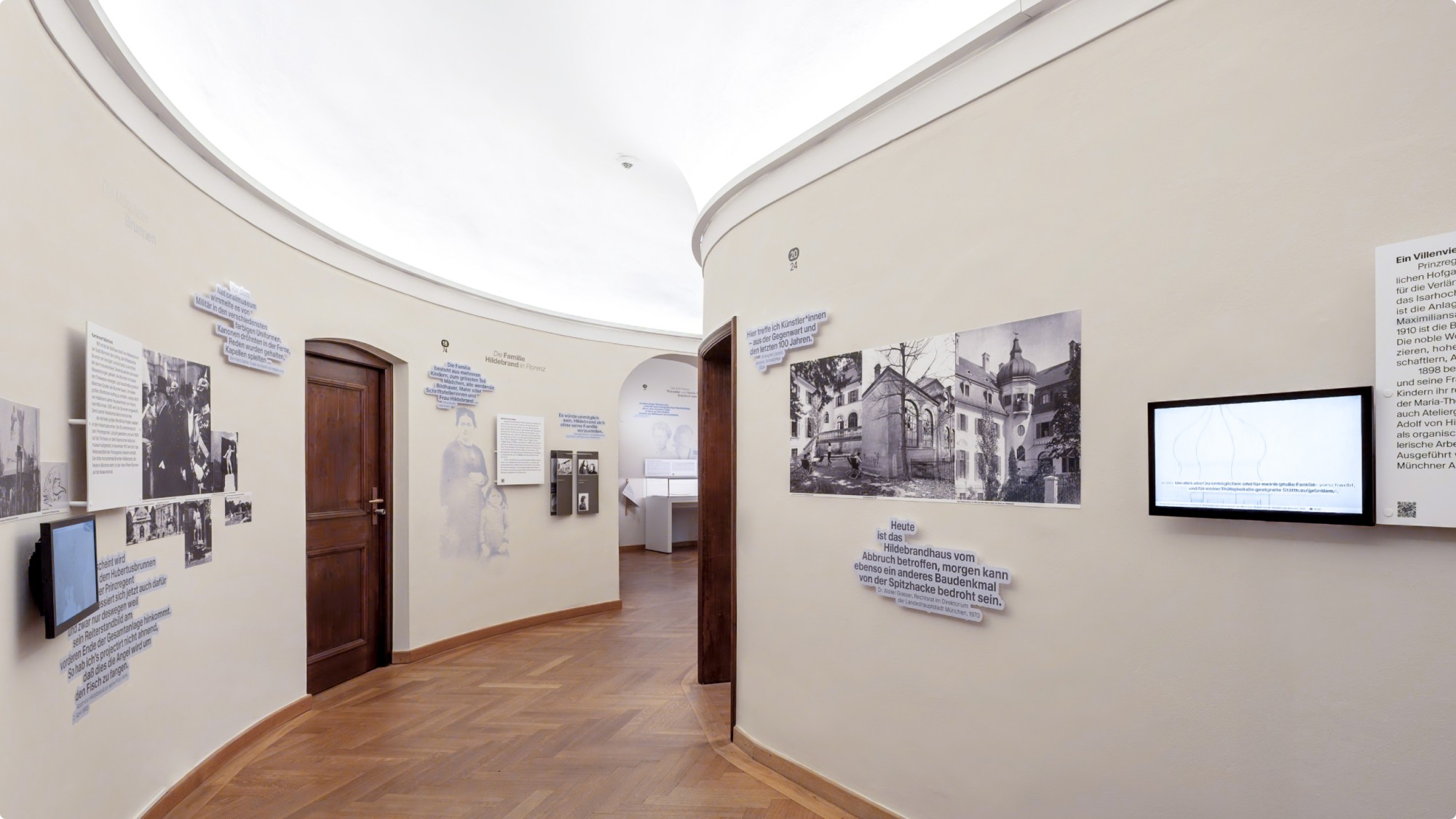 Einblick in die Ausstellung im Flur des Hildebrandhauses. Verschiedenen Infografiken, Bildern und Videos hängen an den Wänden an beiden Seiten.