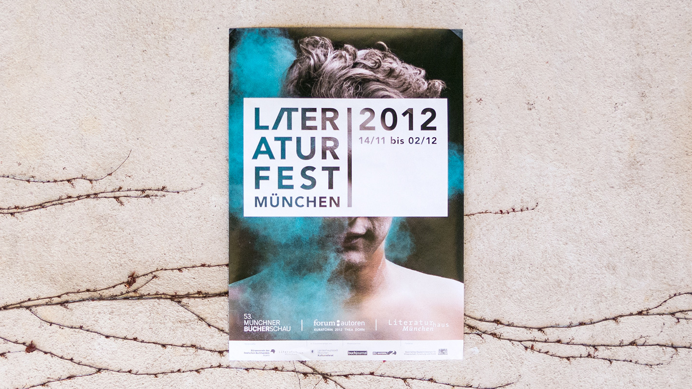 Plakat des Literaturfest 2012. Das Logo steht mittig über einem Foto eines Manns, welcher mit blauem Pulver beworfen wird.