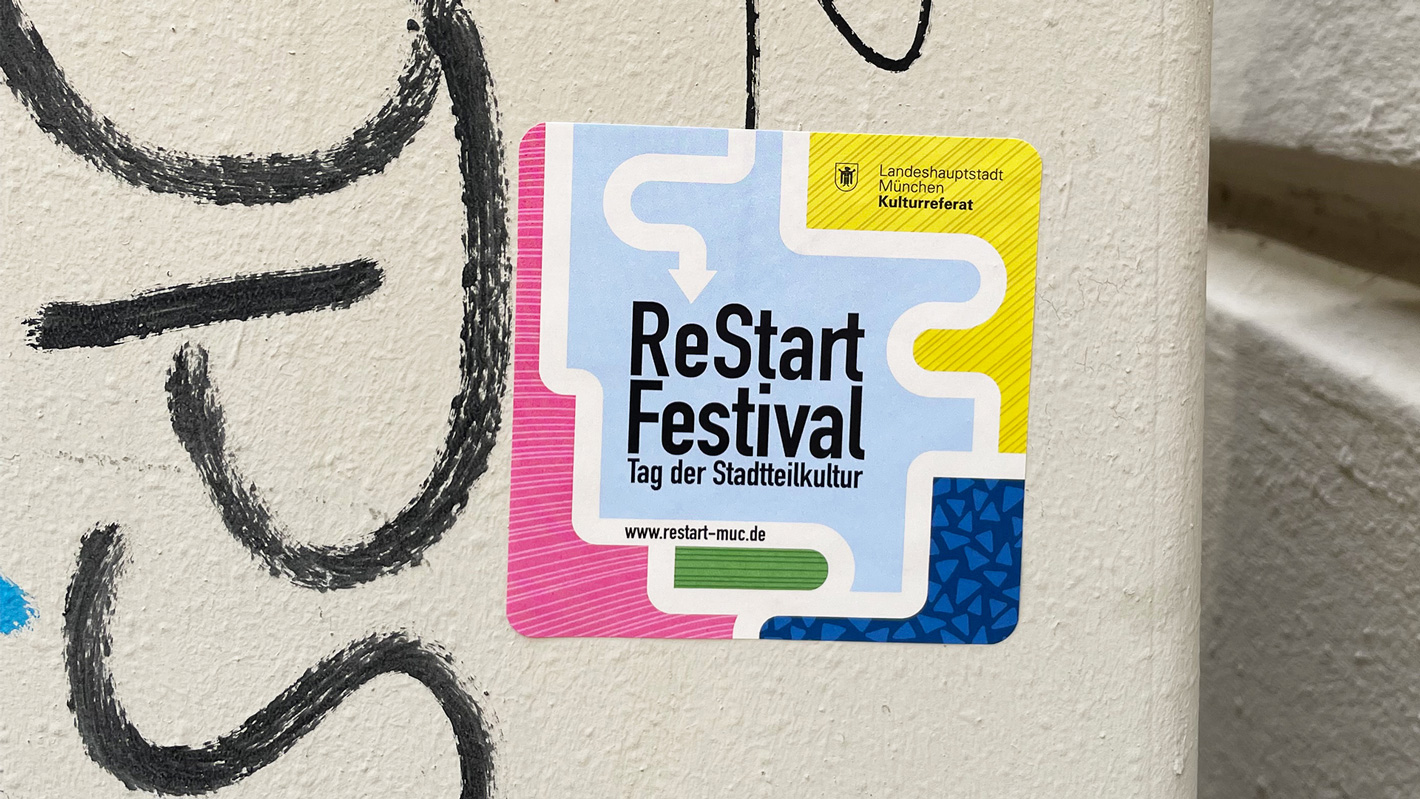 Fotografie eines quadratischen Stickers an einer Hauswand.