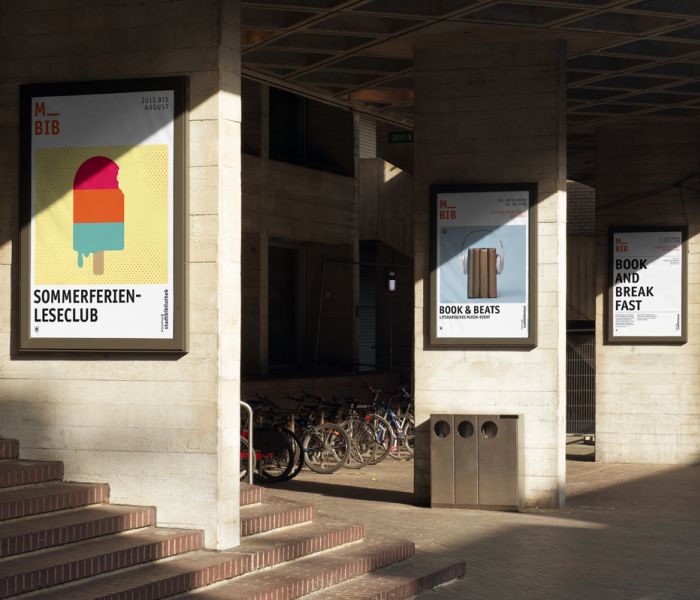 Im Eingangsbereich einer Bibliothek sind drei gestaltete Plakate der Stadtbibliothek zu sehen. Sie bewerben unterschiedliche Veranstaltungen, man erkennt aber sehr leicht, dass Sie von der gleichen marke stammen.