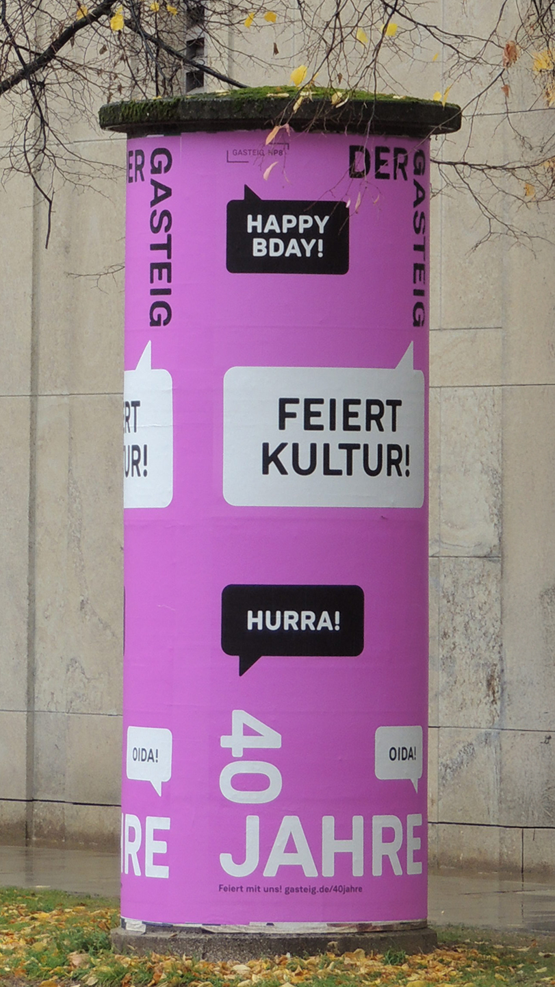 Litfaßsäule mit leuchtend pinkem Keyvisual der Gasteig-Jubiläumskampagne „Feiert Kultur!“ im öffentlichen Raum – typografische Gestaltung zum 40-jährigen Bestehen des Kulturzentrums.