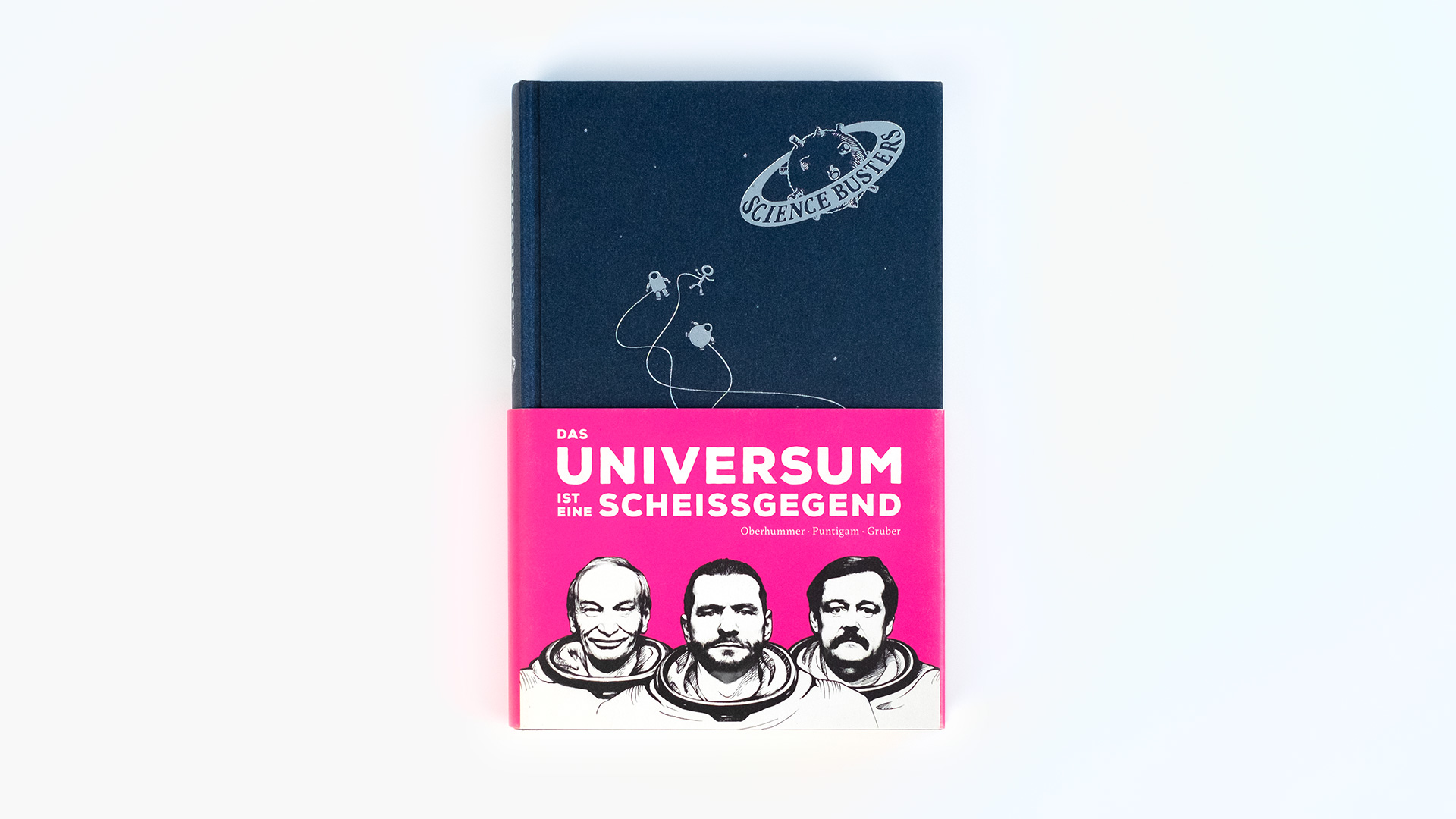 Auf dem Buchcover von „Das Universum ist eine Scheissgegend“ schweben Astronauten vor einem dunkelblauen Hintergrund. Das Buch hat einen pinken Umschlag, auf dem der Titel steht und die 3 Autoren abgebildet sind.